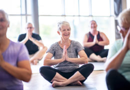 Bien être, bien vieillir, retraitée avec le sourire au qui fait de la meditation assise par terre dans une salle.