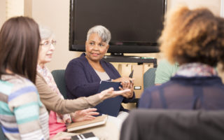 Bien être, bien vieillir, retraitée écoutant une personne parlé dans un groupe de lecture.