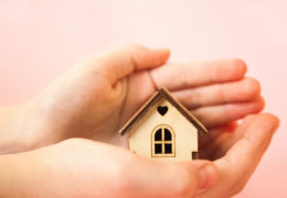 Bien dans mon environnement, des mains tenant une maison en bois miniature