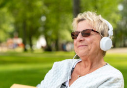 Bien être, bien vieillir, retraitée qui écoute de la musique avec un casque audio dans un parc