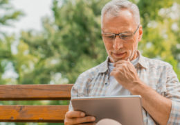 Bien avec mes droits et le numérique, retraité assis dehors entrain d''utiliser une tablette