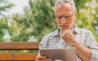 Bien avec mes droits et le numérique, retraité assis dehors entrain d''utiliser une tablette