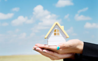 Bien dans mon environnement, mains de femme tenant une maison miniature