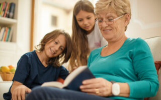 Bien avec les autres, une femme retraitée fait la lecture avec ses deux petits-enfants