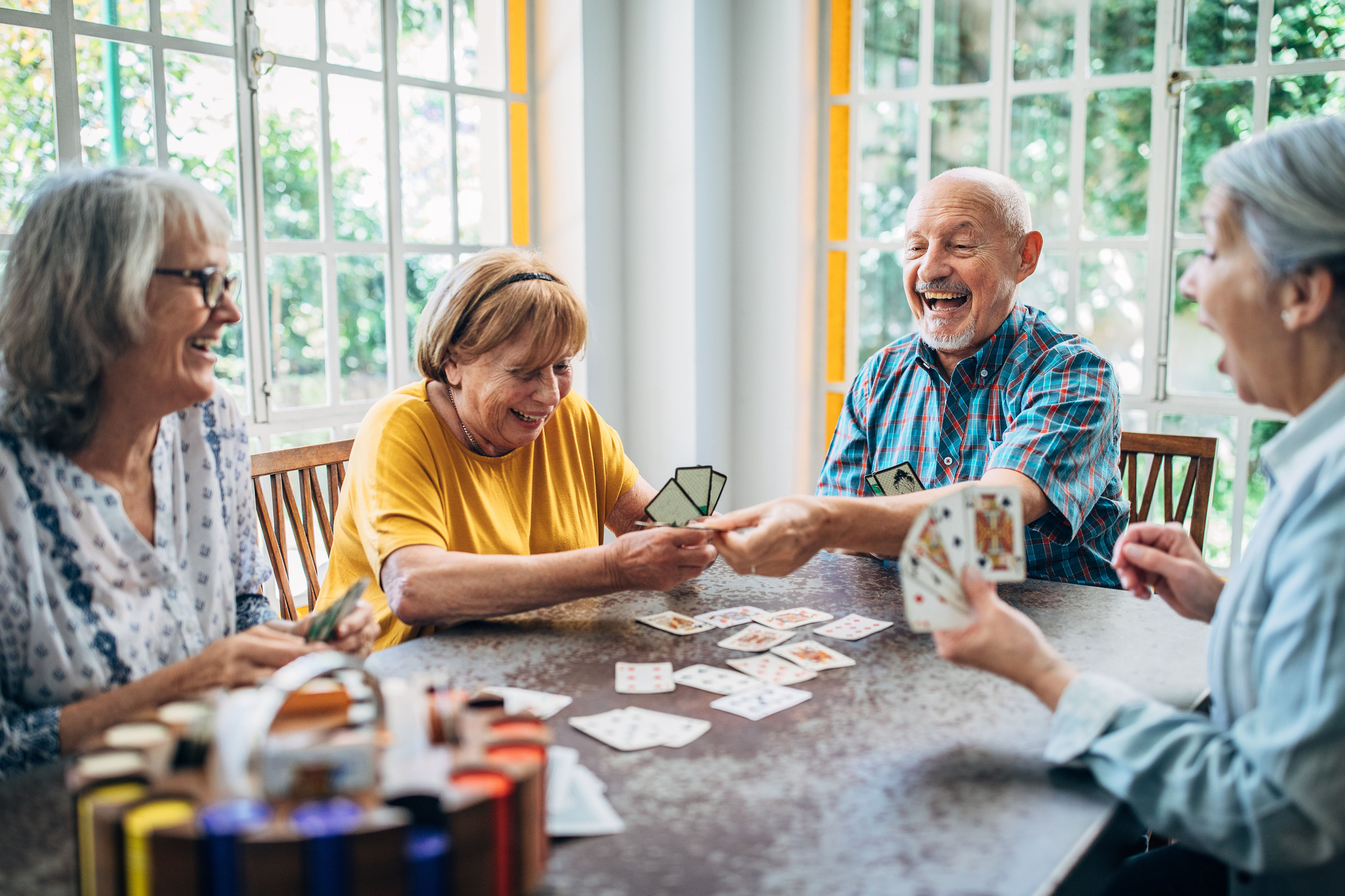 Bien avec les autres, groupe de retraité assis à une table qui rigole et joue aux cartes