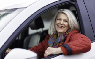 Bien dans mon environnement, une femme accoudée à la fenêtre de sa voiture en souriant