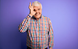 Bien être, bien vieillir, retraité qui fait un rond avec son pouce et son index devant son œil.