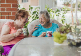 Bien avec les autres, deux retraitées rigolent assises à une table avec une tasse de thé