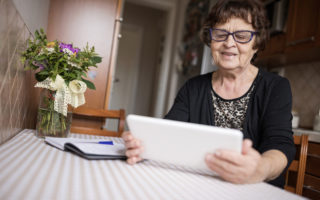Bien avec mes droits et le numérique, retraitée assise à une table qui utilise une tablette