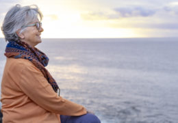 Bien être, bien vieillir, retraitée assise, regardant la mer au loin.