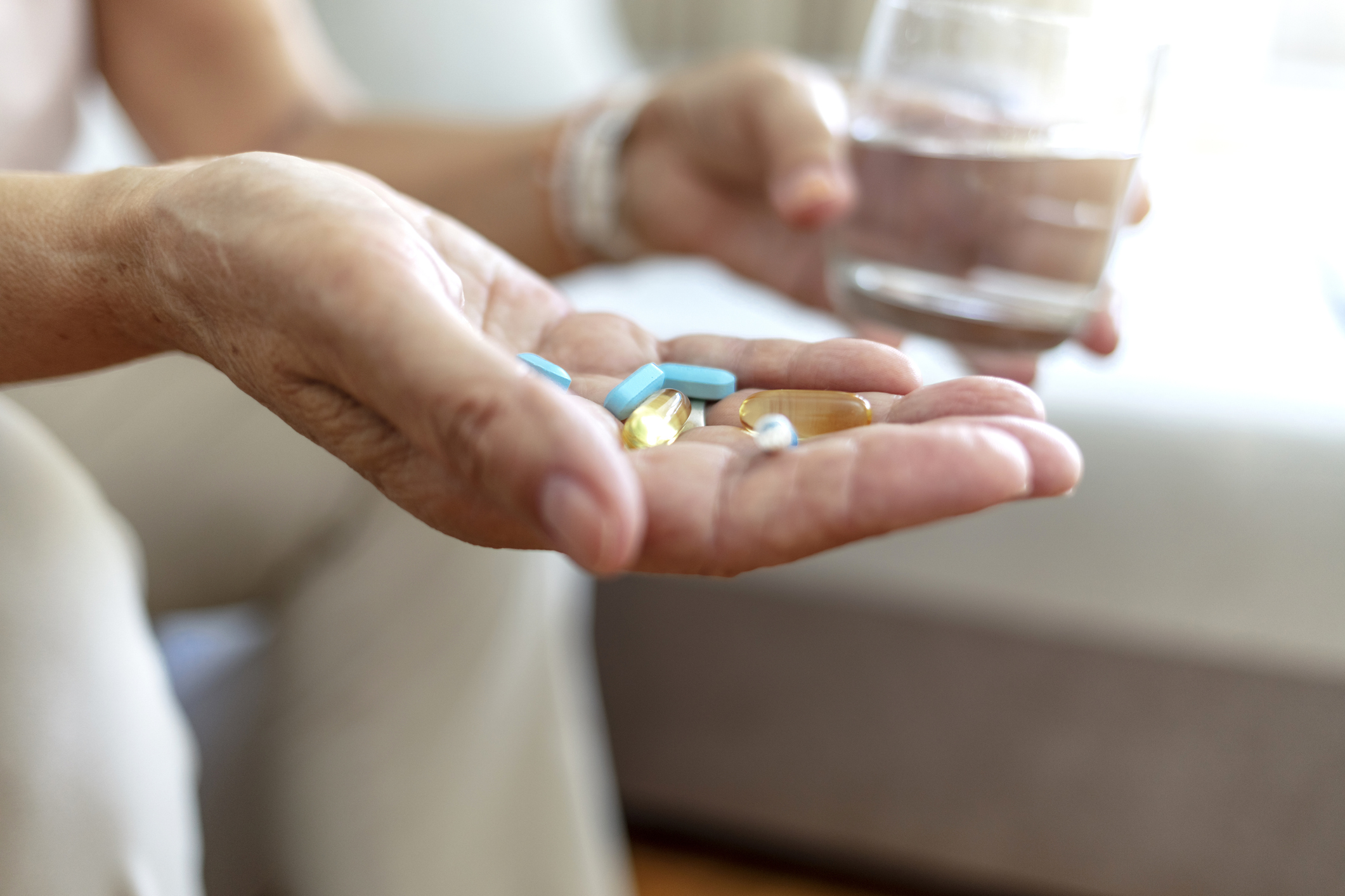 Bien être, bien vieillir, personne avec des médicaments dans une main et un verre d'eau dans l'autre main.