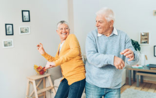 Bien avec mes proches, couple de retraité heureux qui dance dans un salon